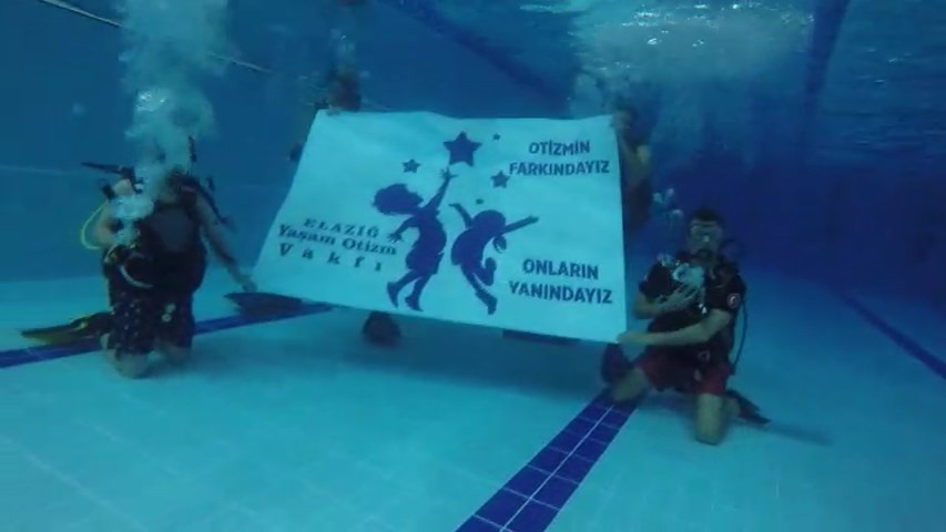 Su altında “Otizmin farkındayız, onların yanındayız” pankartı